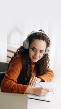 Happy young woman elearning on laptop from home attending webinar with headphones. Smiling student watching virtual class or having web conference meeting on computer