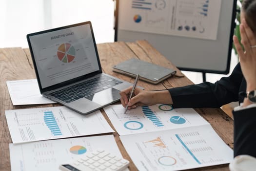 Asian business woman sit at their desks at office and calculate financial graphs showing results about their investments, plan a successful business growth process, diagrams on screen.