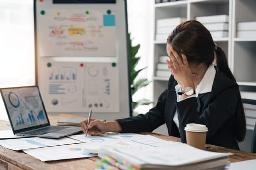 Asian business women are stressed while working on laptop and pile of documents, Tired asian businesswoman with headache at office, feeling sick at work.