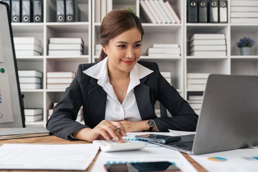 Asian woman business using a calculator calculating financial expense at home office.