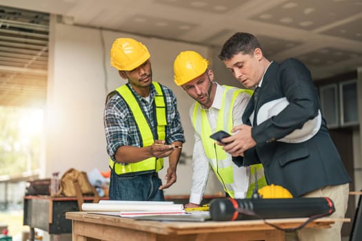 Team Engineers with draft plan of building on constructing site. Engineer work on site. Inspector engineer check and working on site.