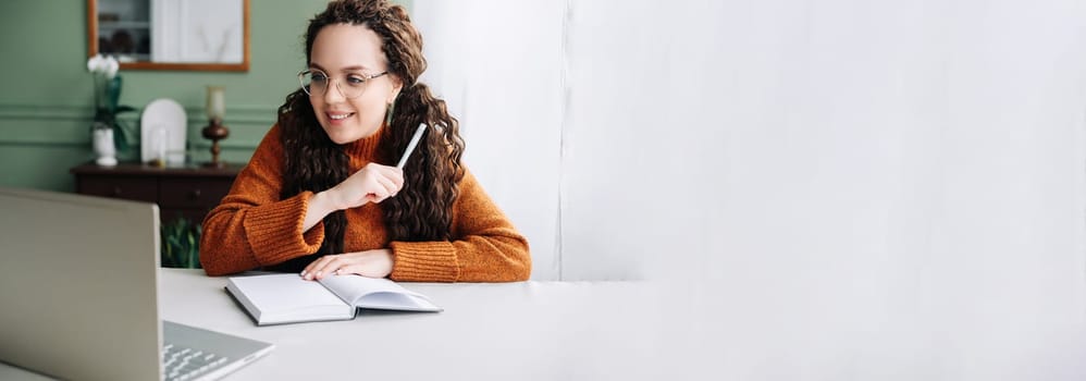 Young Woman Learning and Working Remotely from Home Office with Laptop Computer. Beautiful Young Professional Multi-Tasking with Laptop for Remote Learning and Work.