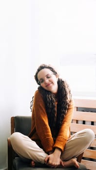 Young woman feeling joyful and relaxed at home. Happy woman enjoying a cozy day at home. Smiling lady feeling content and relaxed in her modern apartment