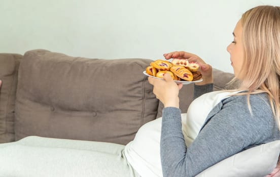 A pregnant woman eats a sweet donut. Selective focus. Food.