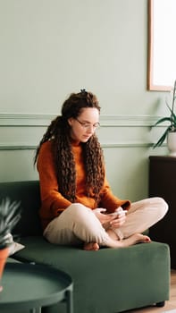 Young woman relaxing and shopping online with smartphone at home. Happy lady enjoying social media on mobile phone at home. Attractive woman using smartphone for entertainment and communication.
