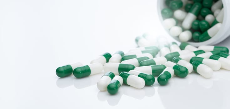 Green and white capsule pill spread out of pill bottle. Healthcare and medicine. Prescription drug. Pharmaceutical industry. Cancer targeted therapy and immunotherapy drug research and development.