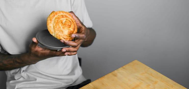 Close up african american hand holding soft layered pastry bun - copy space and empty space for text banner concept