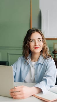 Smiling female corporate employee working on laptop in modern office, marketing manager or businesswoman focused on screen, happy and confident at her desk.