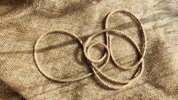 Burlap fabric, coarse jute weave and thick burlap rope. Background, texture, pattern, and frame.