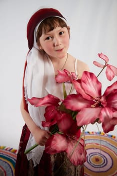 Portrait of Little girl in a stylized Tatar national costume with flowers on a white background in the studio. Photo shoot of funny young teenager who is not a professional model