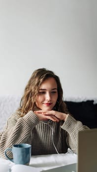 Engaged female freelancer in video conference with employer, attentively discussing project details, smiling at web camera with folded hands under chin