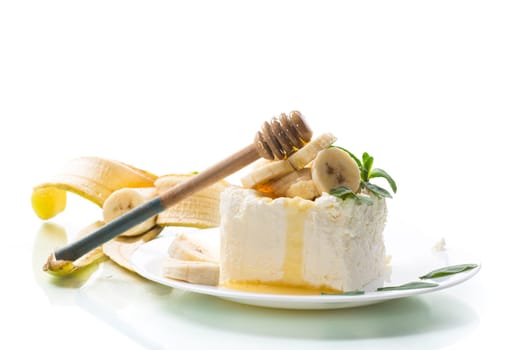 Portion of homemade milk curd with banana slices and honey, isolated on white background.