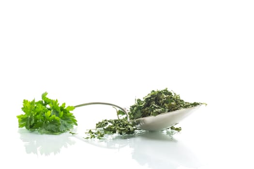 dried parsley in a spoon next to fresh herbs, isolated on white background