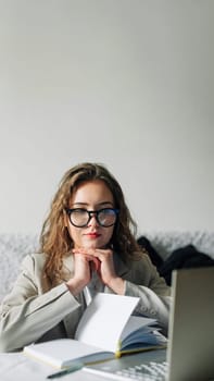 Young serious busy professional businesswoman employee or student wearing glasses using a laptop watching online webinars or training web courses, looking at computers, thinking, and doing research