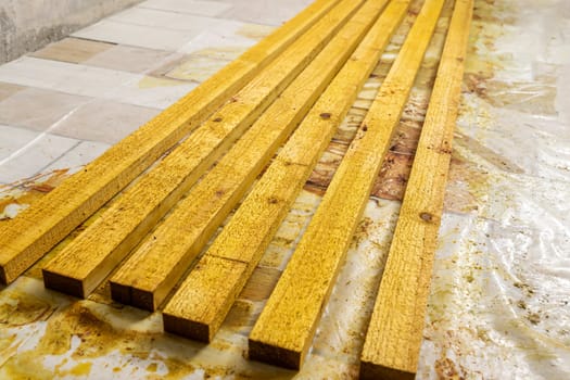 wooden boards treated with protective compounds. painted wooden slats dry on the floor in the workshop. Treatment of wood with a protective compound. Construction, home improvement. impregnation of wooden boards