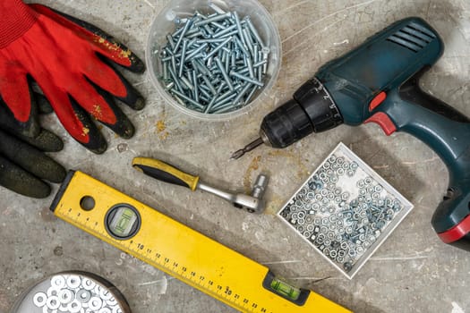 Construction tools on the table. cordless screwdriver, ruler, screws, work protective gloves, wrench, construction level. top view