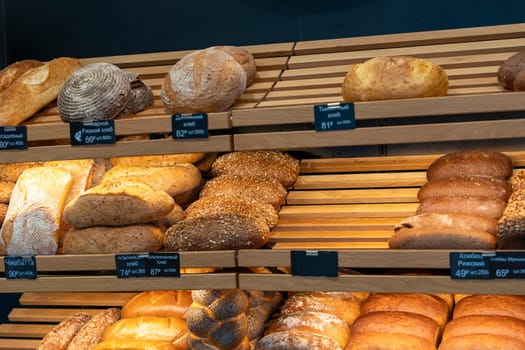 bread and rolls on the shelves of the bread shop. A modern bakery with various types of bread. breads shelves. Bread and fresh pastries wood showcase, bakery products in wooden interior