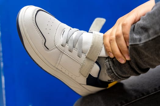 fitting new fashionable sneakers in a shoe store. Buying new modern shoes. Shopping, preparing for school. Close-up of a sport shoe in a shoe store and boy trying it on