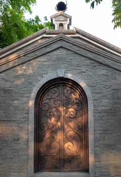 Nakhonsawan, Thailand - Apr 23, 2023 - Antique iron arched door on brick stone wall in a historic brick building. Selective focus.