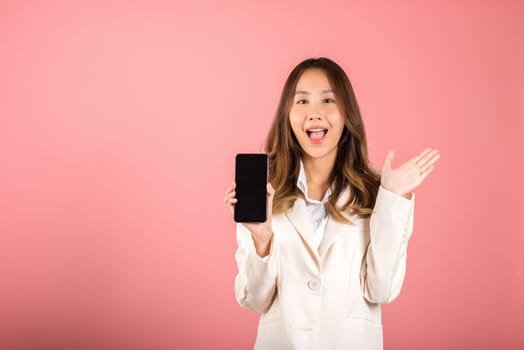 Happy Asian portrait beautiful cute young woman teen smiling excited holding blank screen mobile phone studio shot isolated on pink background, Thai female person showing smartphone empty screen space