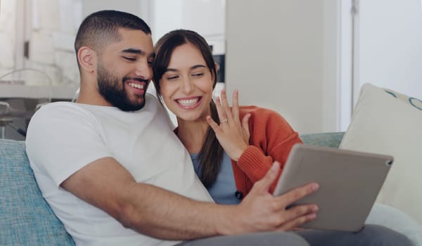 Engagement, announcement and a couple on a video call from a sofa in the living room of their home together. Smile, proud or excited with a happy man and woman sharing good news about their marriage.