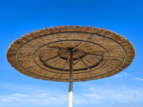 straw beach umbrella against the background a clear blue sky close-up