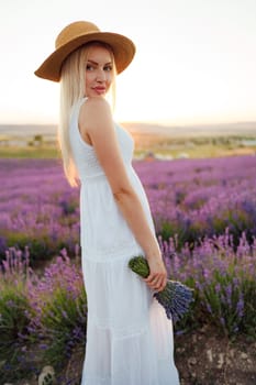 Attractive young woman in summer dress standing among the lavender fields close up