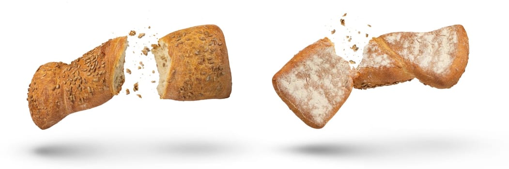 Two loaves of crispy bread isolated on white. Loaves of freshly baked crispy bread are broken in half with crumbs flying in all directions at the break. Top and bottom view. Fresh baking concept