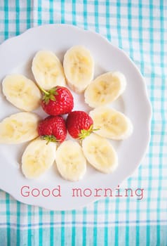 banana and strawberries on a white plate inscription good morning
