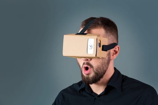 Man using a new virtual reality headset on grey background. Men's emotions