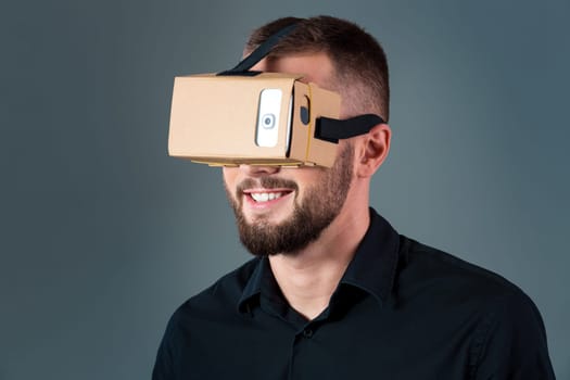 Man using a new virtual reality headset on grey background. Men's emotions