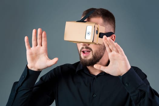 Man using a new virtual reality headset on grey background. Men's emotions