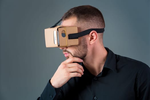 Man using a new virtual reality headset on grey background. Men's emotions