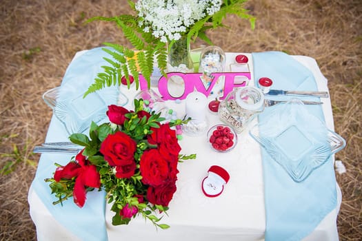 Wedding table setting in nature. Bridal bouquet and ring.