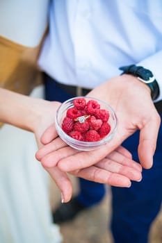 Wedding rings in a bowl with raspberries top view