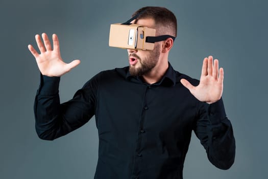 Man using a new virtual reality headset on grey background. Men's emotions
