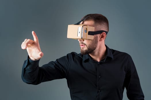 Man using a new virtual reality headset on grey background. Men's emotions