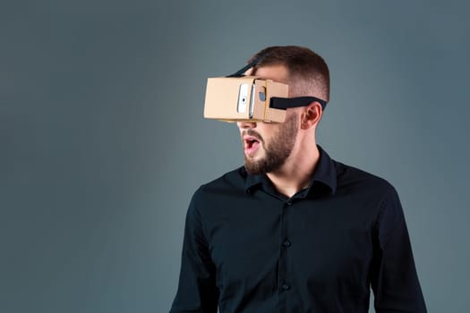 Man using a new virtual reality headset on grey background. Men's emotions