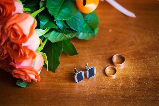 bridal bouquet, groom's ring and cuff links are on the table