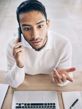 Confused, business man and phone call with laptop, conversation and in office. Asian male, cellphone and talking for startup company, upset for deal and communication problem, smartphone and top view.