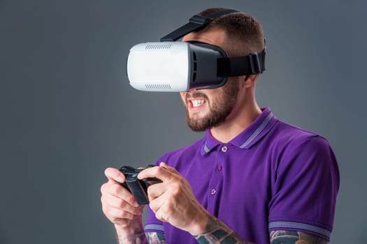 Man in studio wearing virtual reality headset playing game. Man dressed in a purple T-shirt