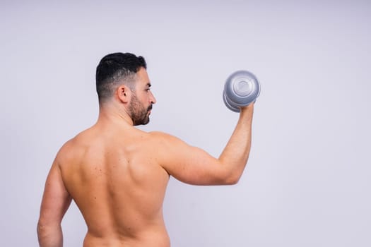 Athletic man doing exercises with dumbbell at biceps on a white background. Strength and motivation