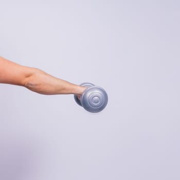 Athletic man doing exercises with dumbbell at biceps on a white background. Strength and motivation
