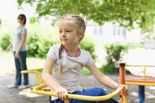 Portrait of a beautiful girl on the playground at a swing