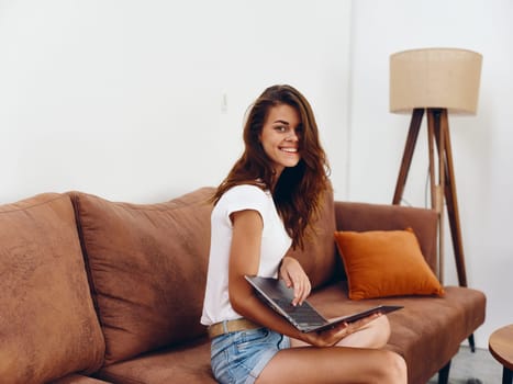 Woman freelancer sitting on the couch with a laptop beautiful smile , modern stylish interior Scandinavian lifestyle, copy space. High quality photo