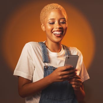 Black woman, phone and smile for social media, communication or chatting against a studio background. Happy African American female smiling or laughing for funny joke, meme or post on smartphone.
