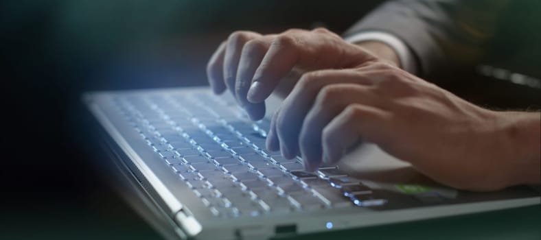 Close-up of male hands typing on a computer keyboard.