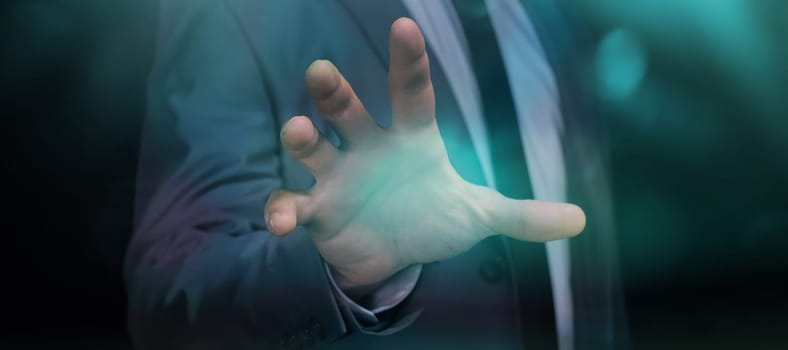 A businessman works with an imaginary hologram by touching it with his hand with an open palm.