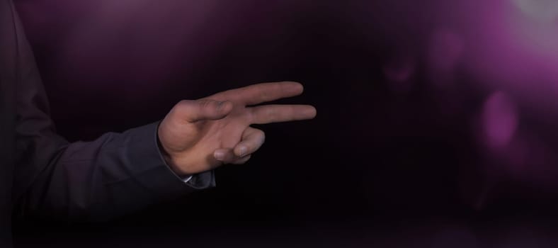 On a dark background, the hand of a businessman presenting an invisible object.