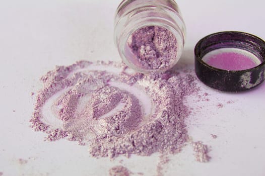 Pearlescent sparkling eye shadow scattered on the table, a jar of shadows.